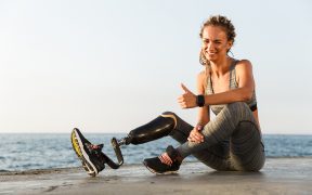 Image of a woman athlete with a prosthetic leg stretching at the beach for The Rise of the Otherwise-Abled blog post