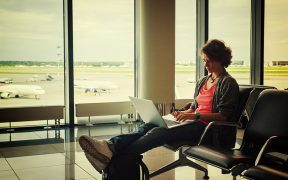 Image of a woman working on her laptop sitting in an airport for Canada and the Changing Nature of Work blog post