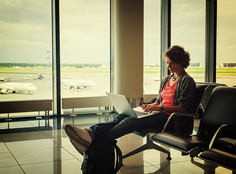 Image of a woman working on her laptop sitting in an airport for Canada and the Changing Nature of Work blog post