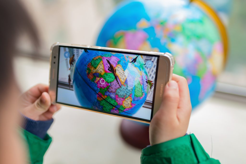 Child using phone to look at globe to play augmented reality game