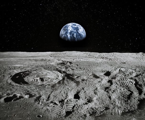 Surface of the moon with the earth rising on the horizon.