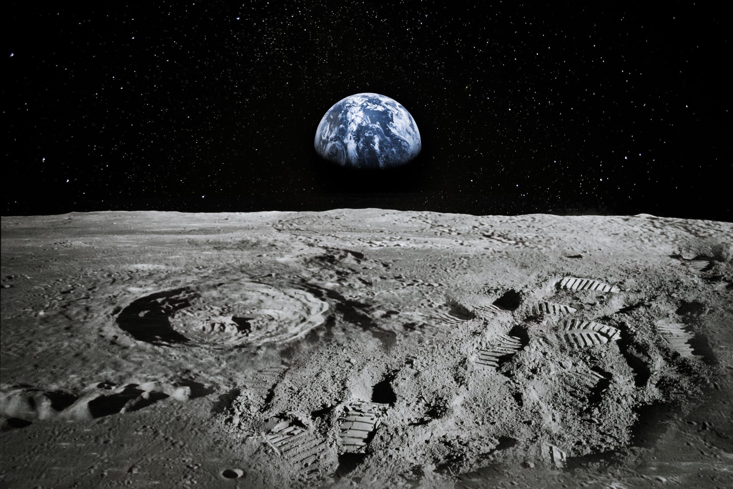 Surface of the moon with the earth rising on the horizon.